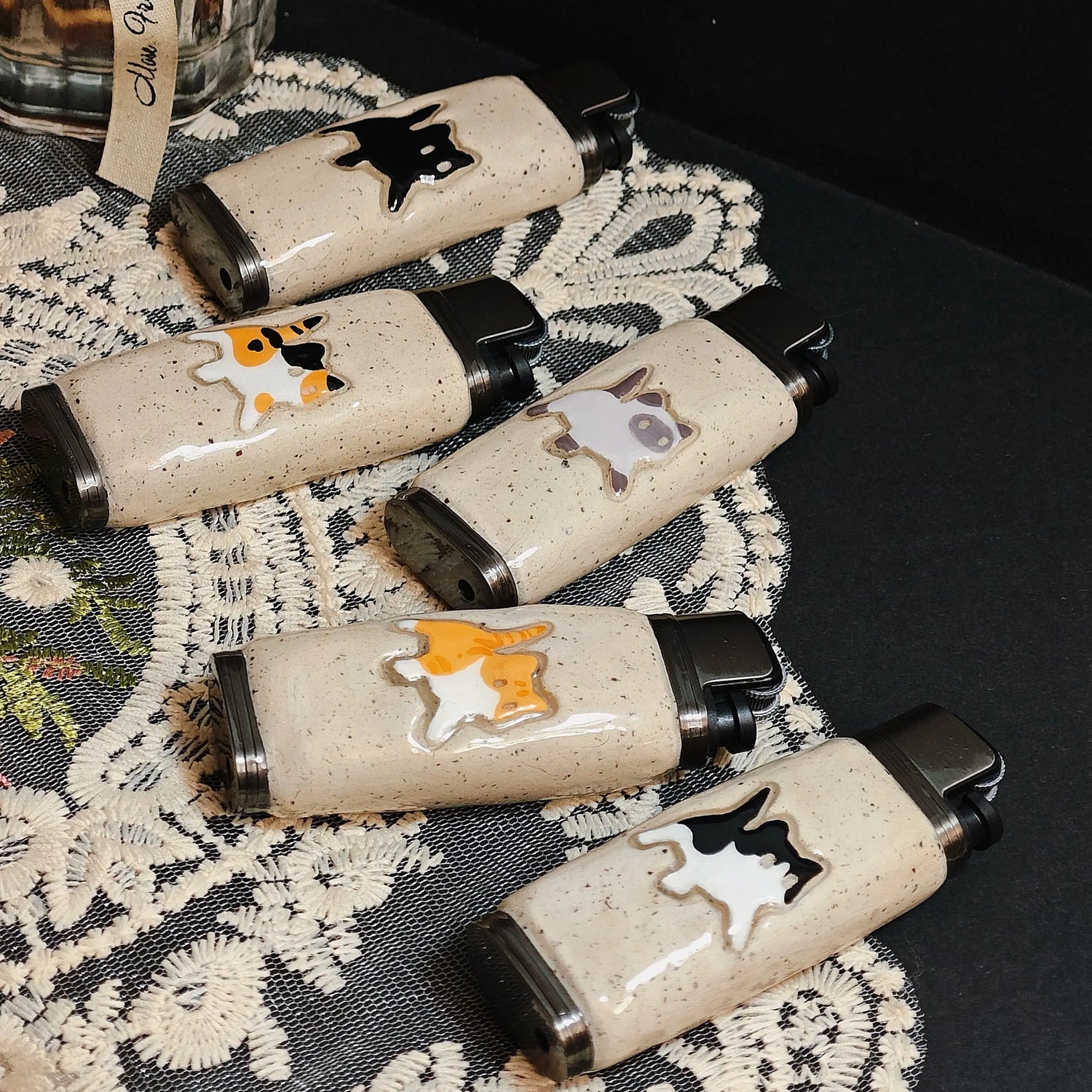 Ceramic lighter cases with cute cat and animal designs from Mellow Sora on lace fabric