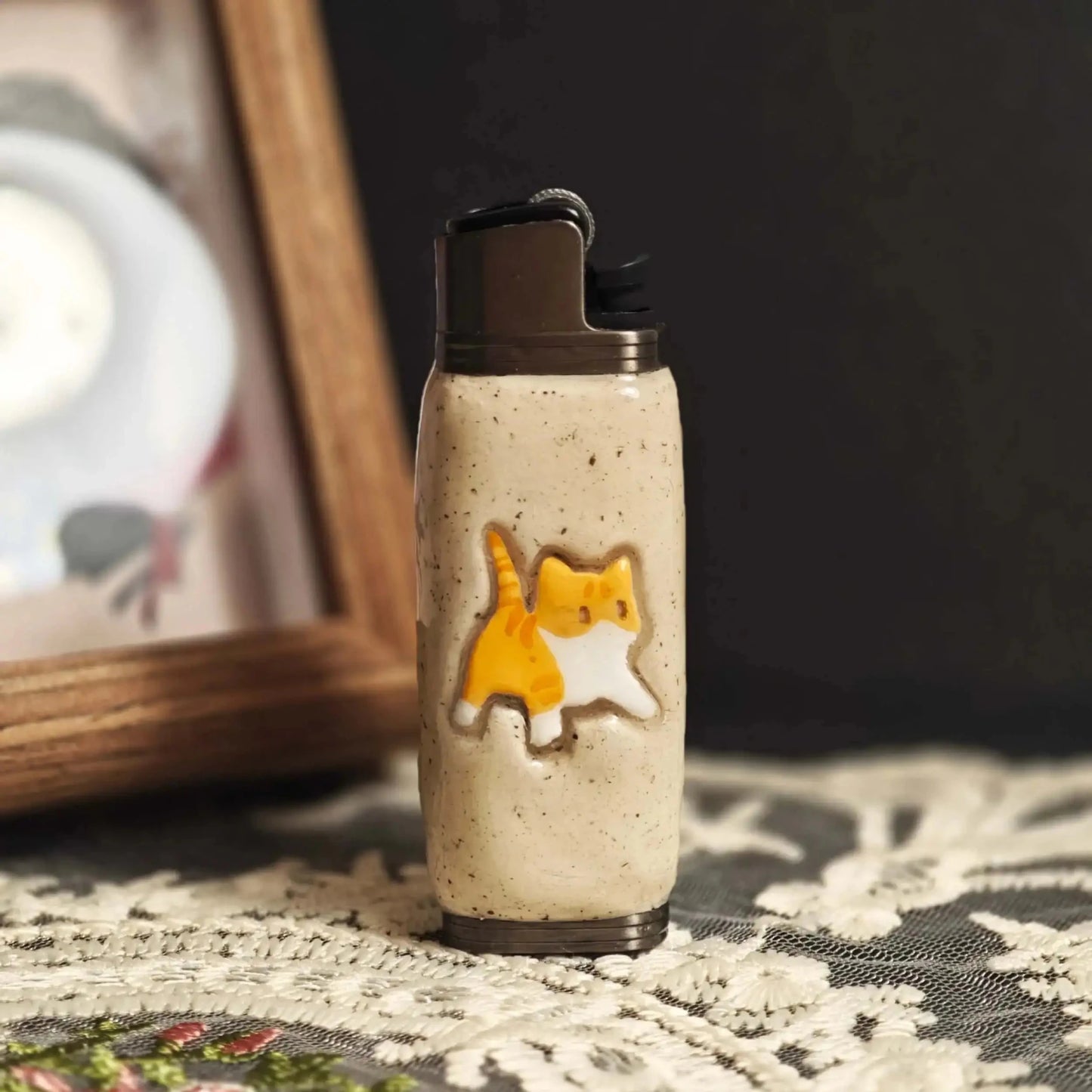 Beige Mellow Sora lighter case with cute orange cat design on a lace tablecloth