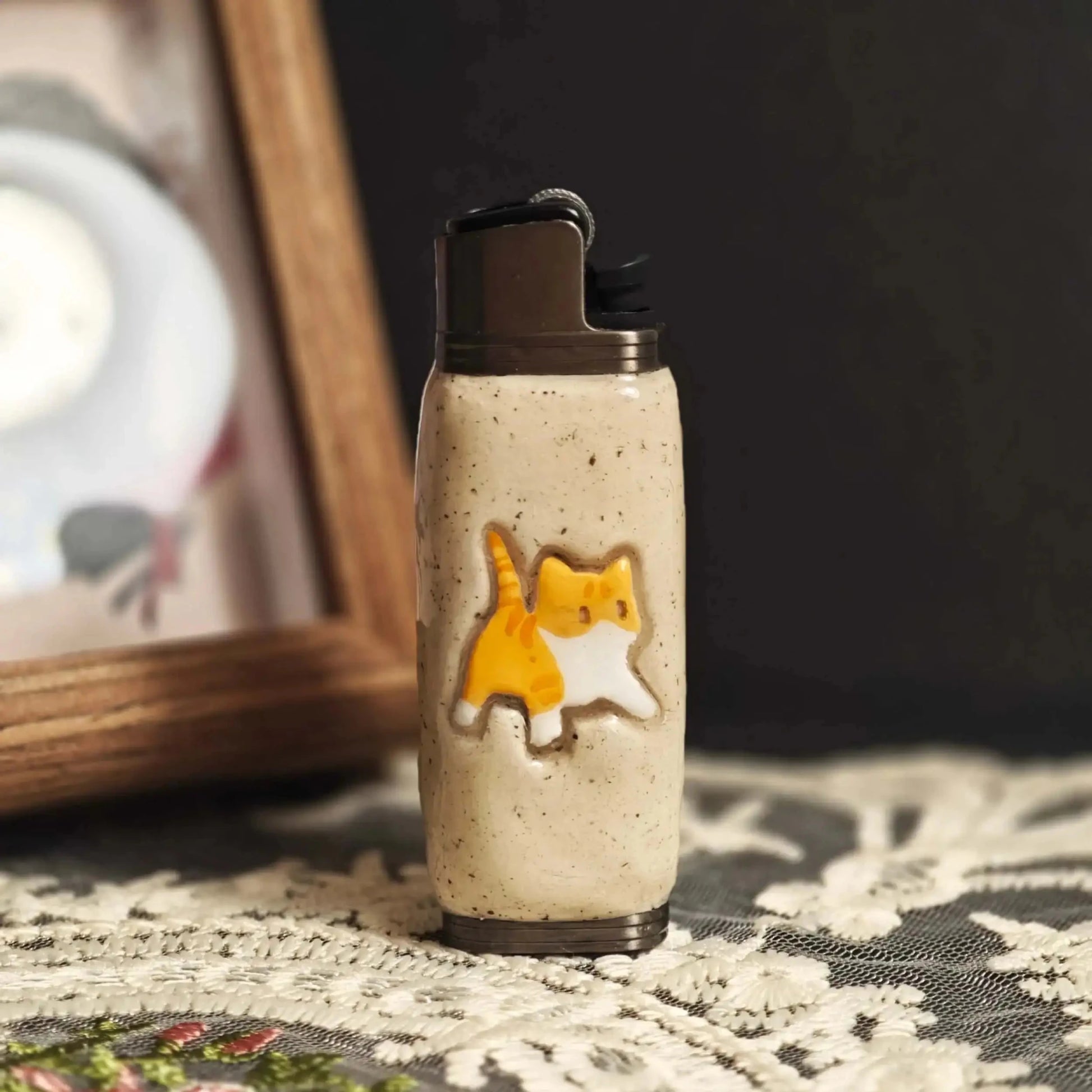 Beige Mellow Sora lighter case with cute orange cat design on a lace tablecloth