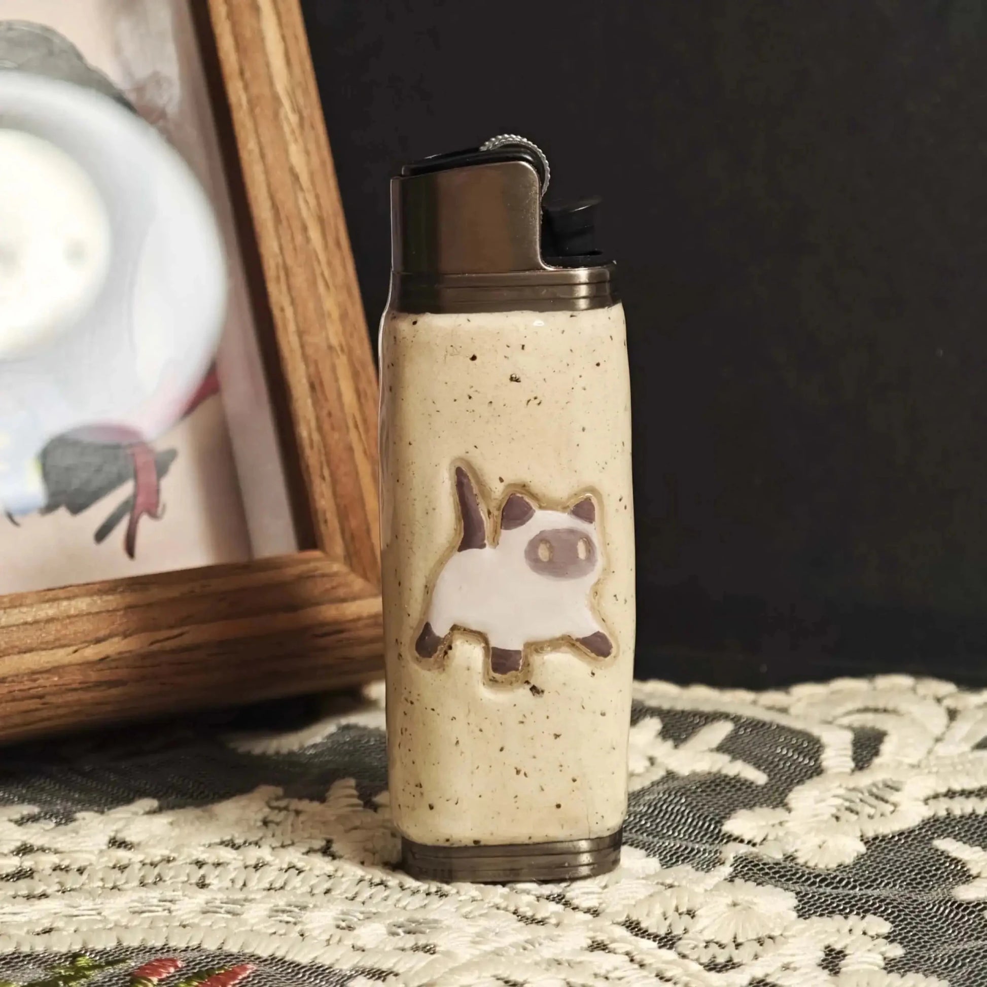 Ceramic lighter case with cat design on lace tablecloth, Mellow Sora lifestyle accessory