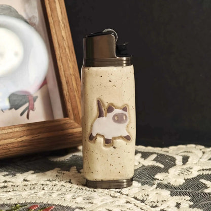 Ceramic lighter case with cat design on lace tablecloth, Mellow Sora lifestyle accessory